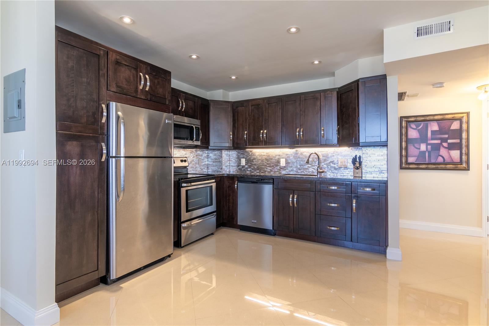 A kitchen features dark wood cabinets, stainless steel appliances, and light-colored tile flooring — 1965 S Ocean Dr # 9F, Hallandale Beach FL 33009, HALLANDALE BEACH, FL