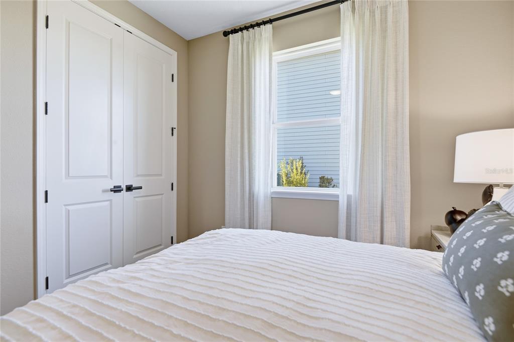 A bedroom features a white closet, a window with curtains, and a bed with pillows — 218 THORNBERRY WAY, PALM COAST, FL