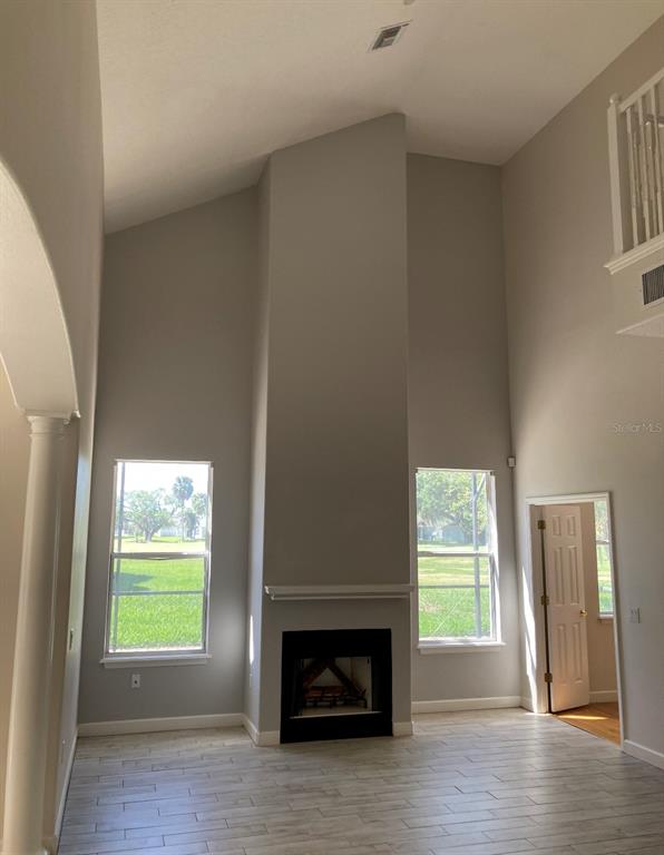 A living room features a tall fireplace, light-colored tile floors, and two windows — 2102 BUNKER VIEW COURT, KISSIMMEE, FL