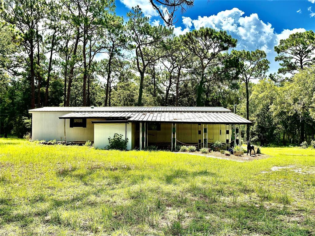 A single-story house with a metal roof and a covered porch sits in a grassy yard — 10780 S FLUTTER TERRACE, INVERNESS, FL