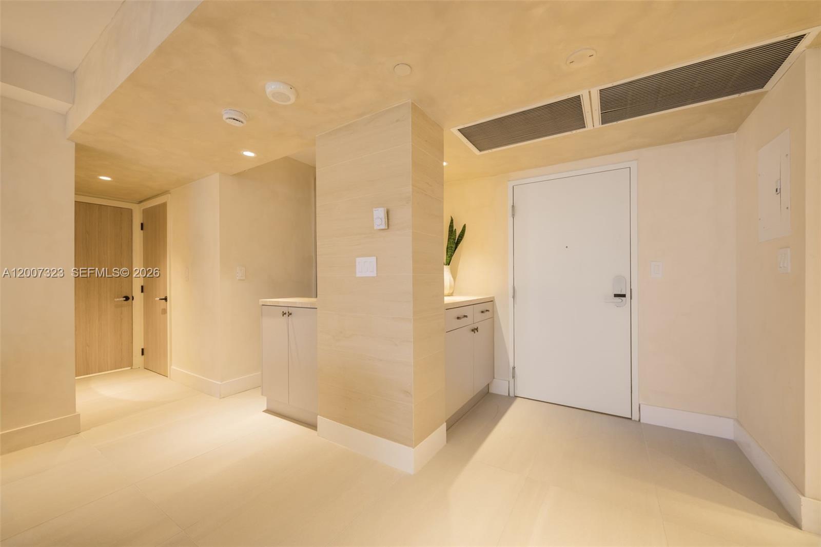 This interior view shows a hallway with light-colored tile flooring, wood-paneled cabinetry, and doors — 2301 Collins Ave # 526, Miami Beach FL 33139, MIAMI BEACH, FL