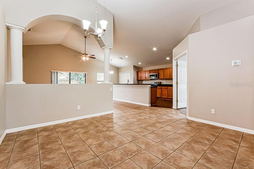 An open-concept dining area with tile flooring leads into a kitchen with wooden cabinets — 4222 BARNSLEY LANE, TAVARES, FL