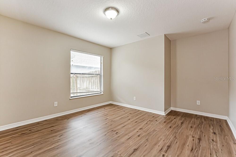 An empty bedroom features light-colored walls, a single window, and wood-look flooring — 4222 BARNSLEY LANE, TAVARES, FL