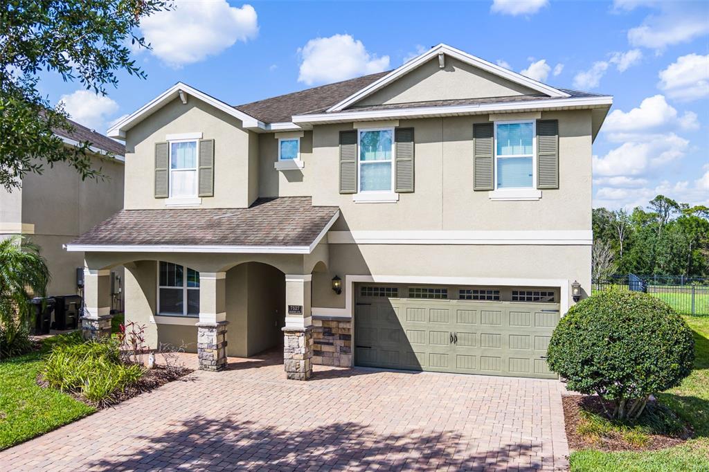 A two-story suburban house features a stone-accented porch, a paved driveway, and a garage — 7527 MARKER AVENUE, KISSIMMEE, FL