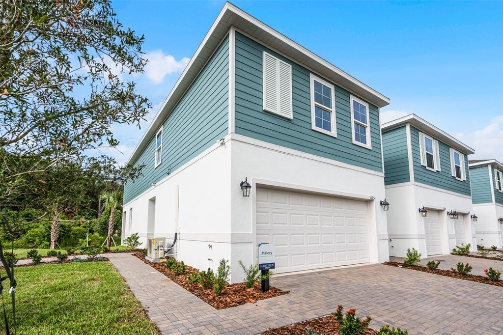 A two-story townhouse with teal siding, white stucco, and a paved driveway — 1148 CYPRESS ELM DRIVE, DELAND, FL