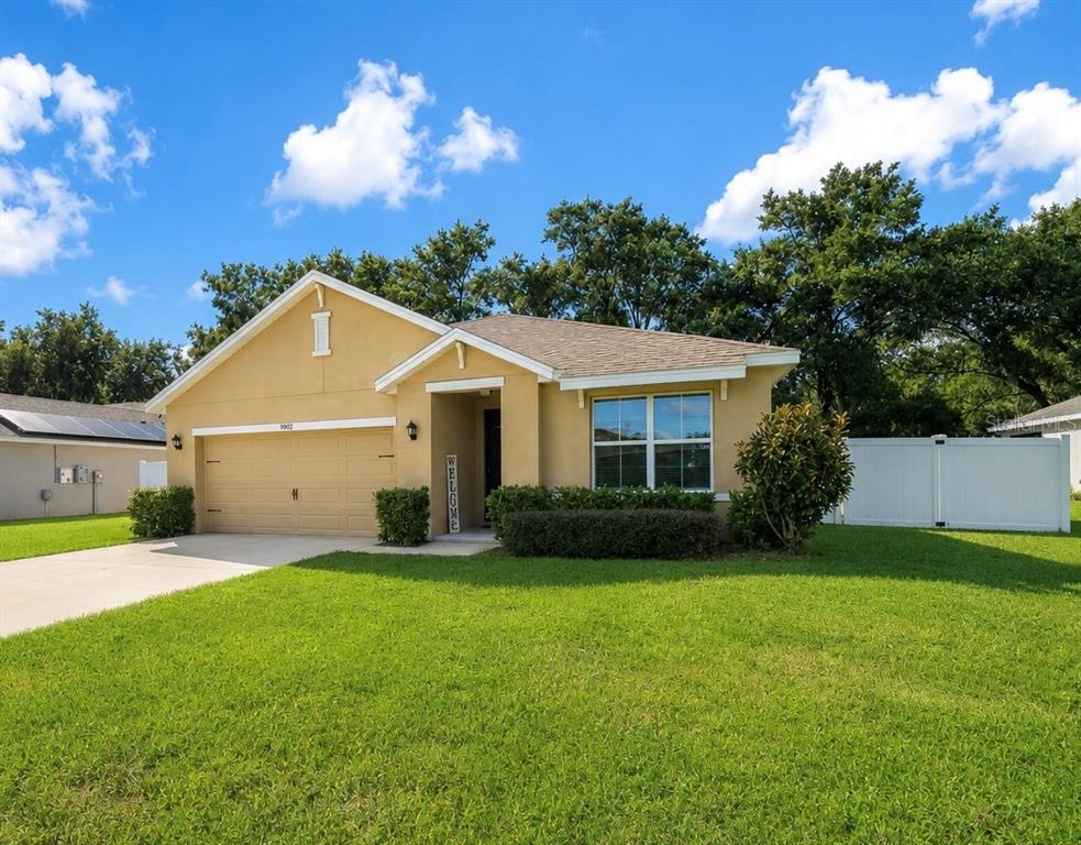 A single-story yellow stucco house with a two-car garage and a front lawn — 9902 SE 37TH TERRACE, BELLEVIEW, FL