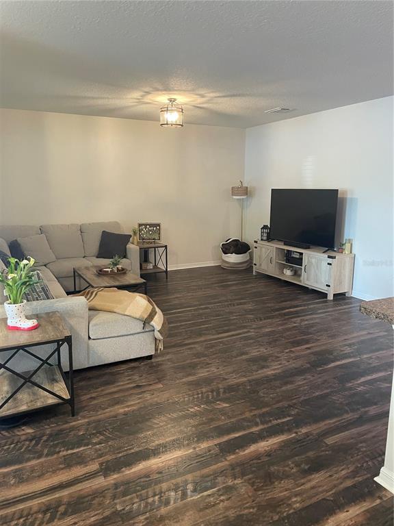 A living room features a sectional sofa, a television console, and dark wood-look flooring — 9902 SE 37TH TERRACE, BELLEVIEW, FL