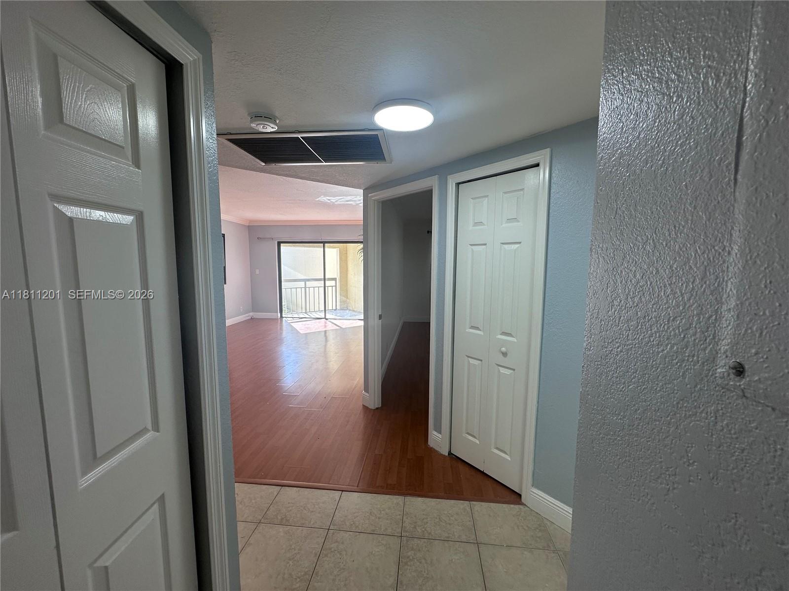 A tiled entryway leads to a living area with wood-look flooring and a sliding glass door — 8290 Lake Dr # 502, Doral FL 33166, DORAL, FL