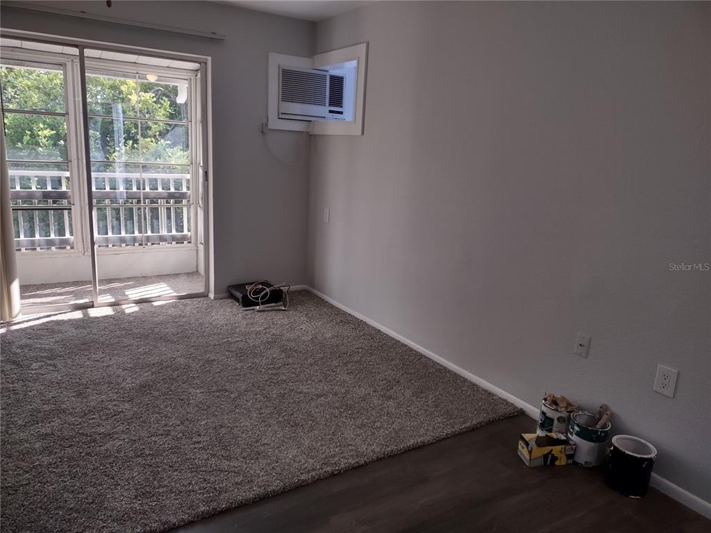 A small kitchen features white cabinets, a black refrigerator, a granite island, and wood flooring — 1538 PLEASANT ROAD UNIT G34, BRADENTON, FL