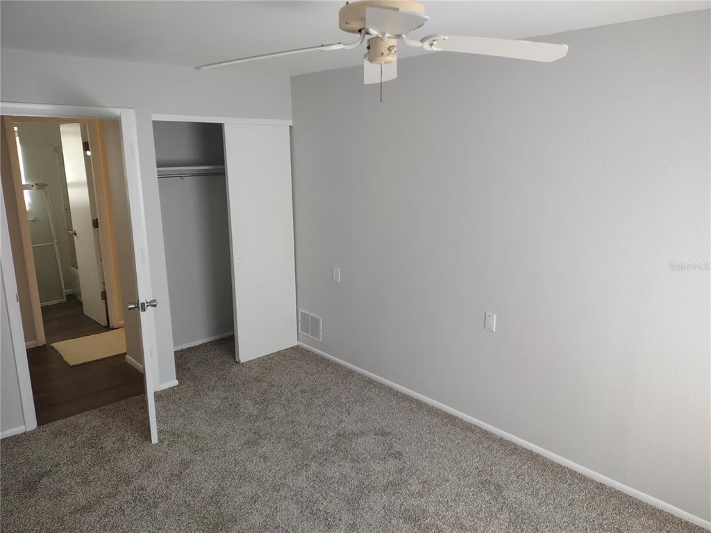 A bedroom features gray walls, gray carpet, a ceiling fan, and an open closet — 1538 PLEASANT ROAD UNIT G34, BRADENTON, FL