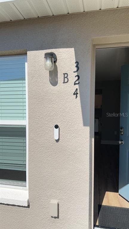 The exterior view shows a light-colored wall with a house number, light fixture, and doorbell — 324 AVENUE Y NE UNIT B, WINTER HAVEN, FL