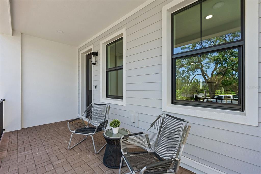 A covered porch features gray horizontal siding, two modern chairs, a small table, and windows — 423 11TH AVENUE S, ST PETERSBURG, FL