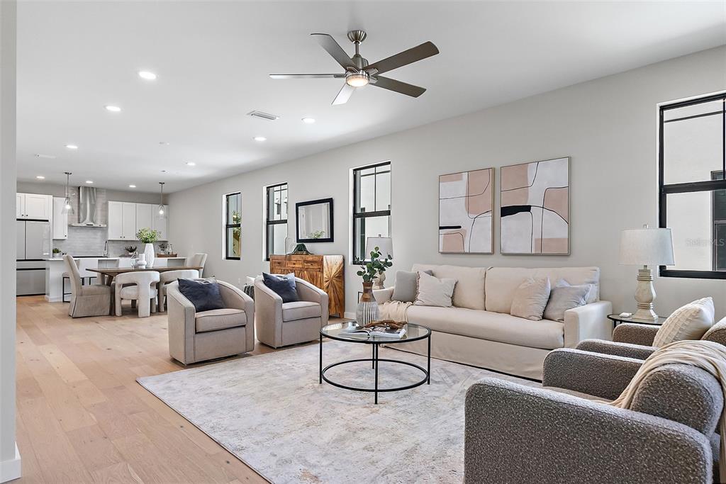 An open-concept living room and kitchen featuring light wood floors, neutral furniture, and recessed lighting — 423 11TH AVENUE S, ST PETERSBURG, FL