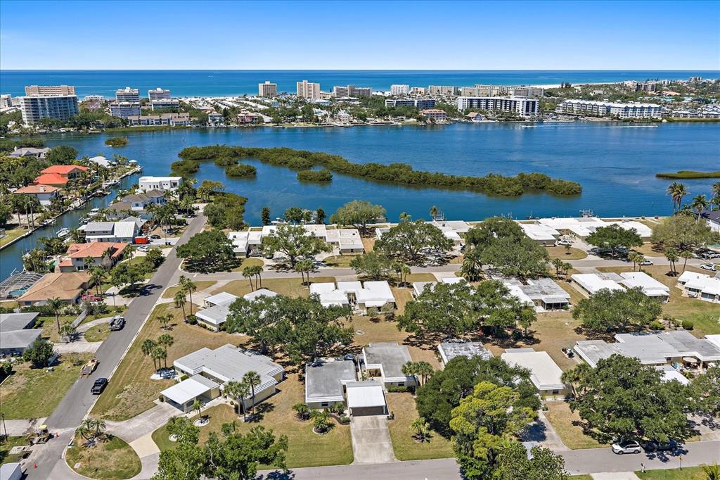 An aerial view shows a residential neighborhood with white-roofed houses near a bay and ocean — 5940 DRIFTWOOD AVENUE UNIT 15, SARASOTA, FL