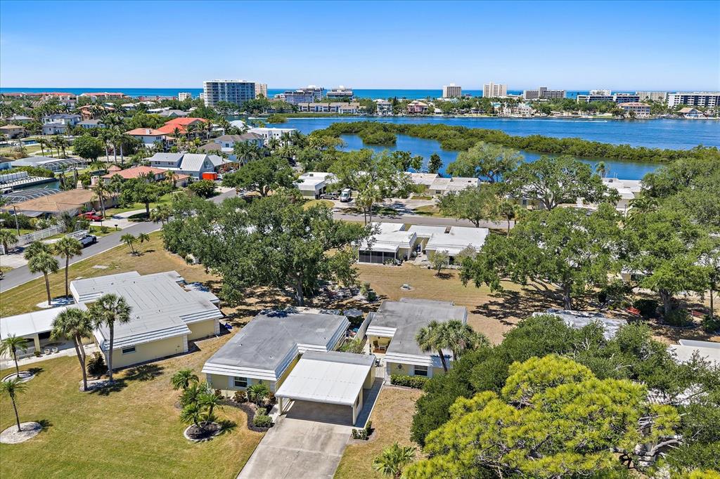An aerial view shows several single-story houses with carports surrounded by trees and grassy lawns — 5940 DRIFTWOOD AVENUE UNIT 15, SARASOTA, FL