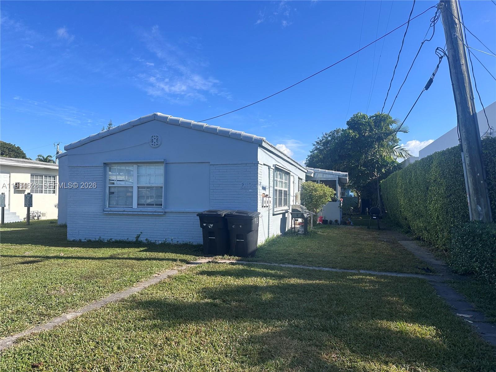 A light blue, single-story house with a brick exterior sits on a grassy lawn — 2125 Bay Dr # C, Miami Beach FL 33141, MIAMI BEACH, FL