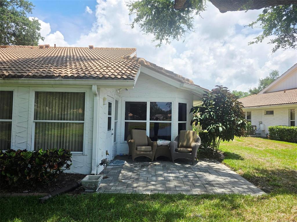 A paved patio with two wicker chairs sits outside the white exterior of a house — 5808 GARDEN LAKES DRIVE, BRADENTON, FL