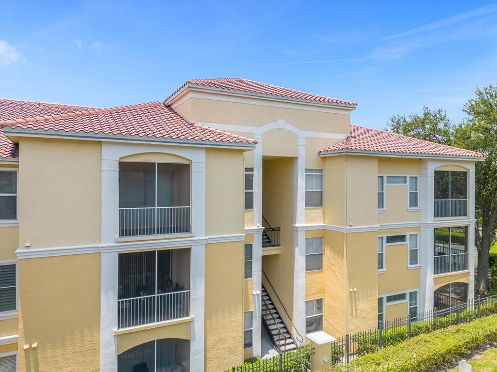 A three-story apartment building with yellow stucco walls, white trim, and a red tile roof — 1475 LAKE SHADOW CIRCLE UNIT 6105, MAITLAND, FL