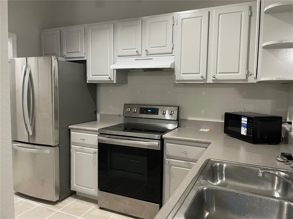 A kitchen features white cabinets, stainless steel appliances, and a gray countertop — 1475 LAKE SHADOW CIRCLE UNIT 6105, MAITLAND, FL