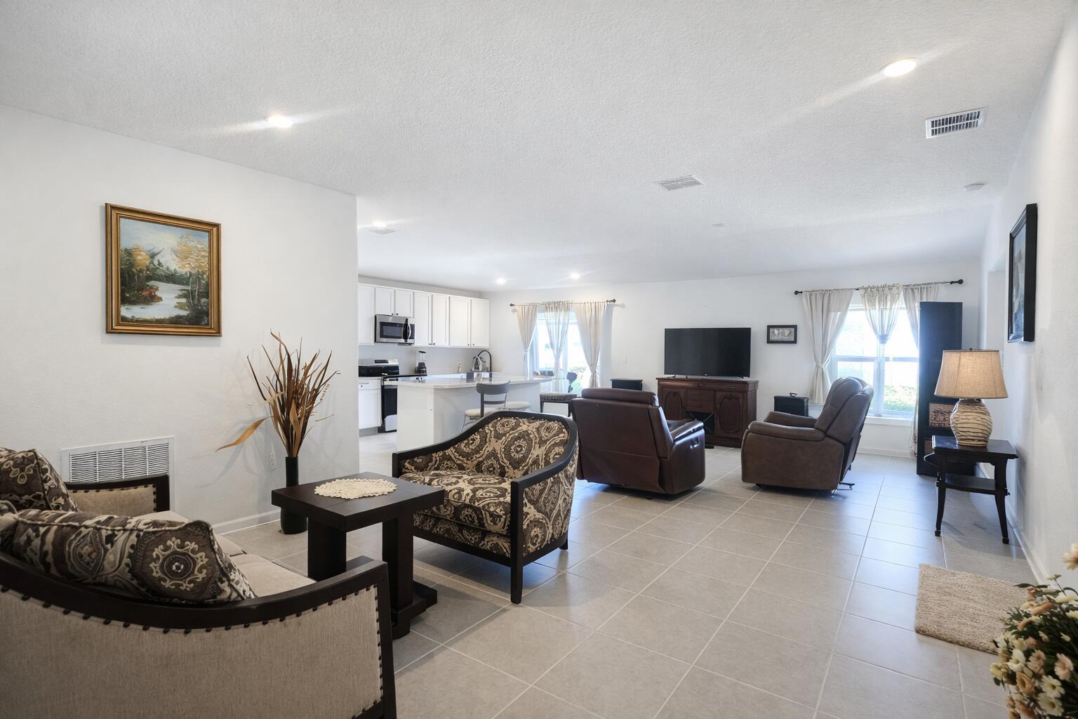An open-concept living room and kitchen area with tile flooring and neutral walls — 1681 Teagan Lane, Winter Haven FL 33884, WINTER HAVEN, FL