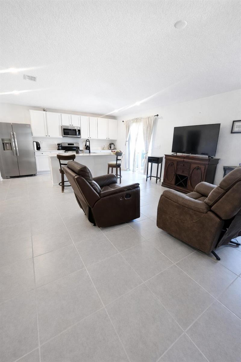 A living room with two brown recliners faces a television and an open-concept white kitchen — 1681 Teagan Lane, Winter Haven FL 33884, WINTER HAVEN, FL