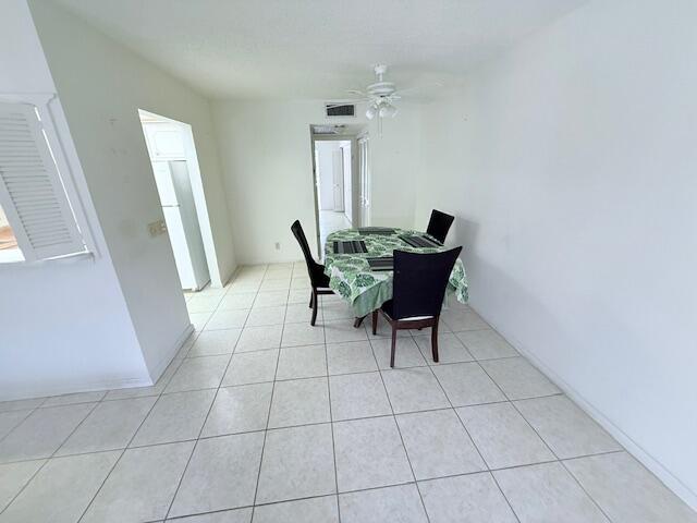 A dining area with a table, four chairs, white walls, and light-colored tile flooring — 128 Upminster F Crescent, Deerfield Beach FL 33442, DEERFIELD BEACH, FL