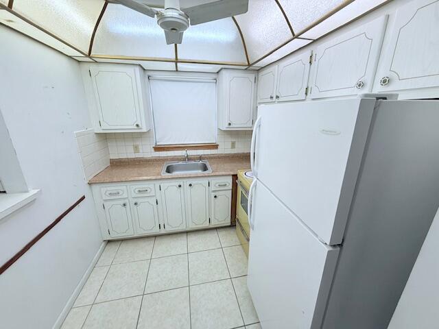 A kitchen features white cabinets, a beige countertop, a stainless steel sink, and white appliances — 128 Upminster F Crescent, Deerfield Beach FL 33442, DEERFIELD BEACH, FL