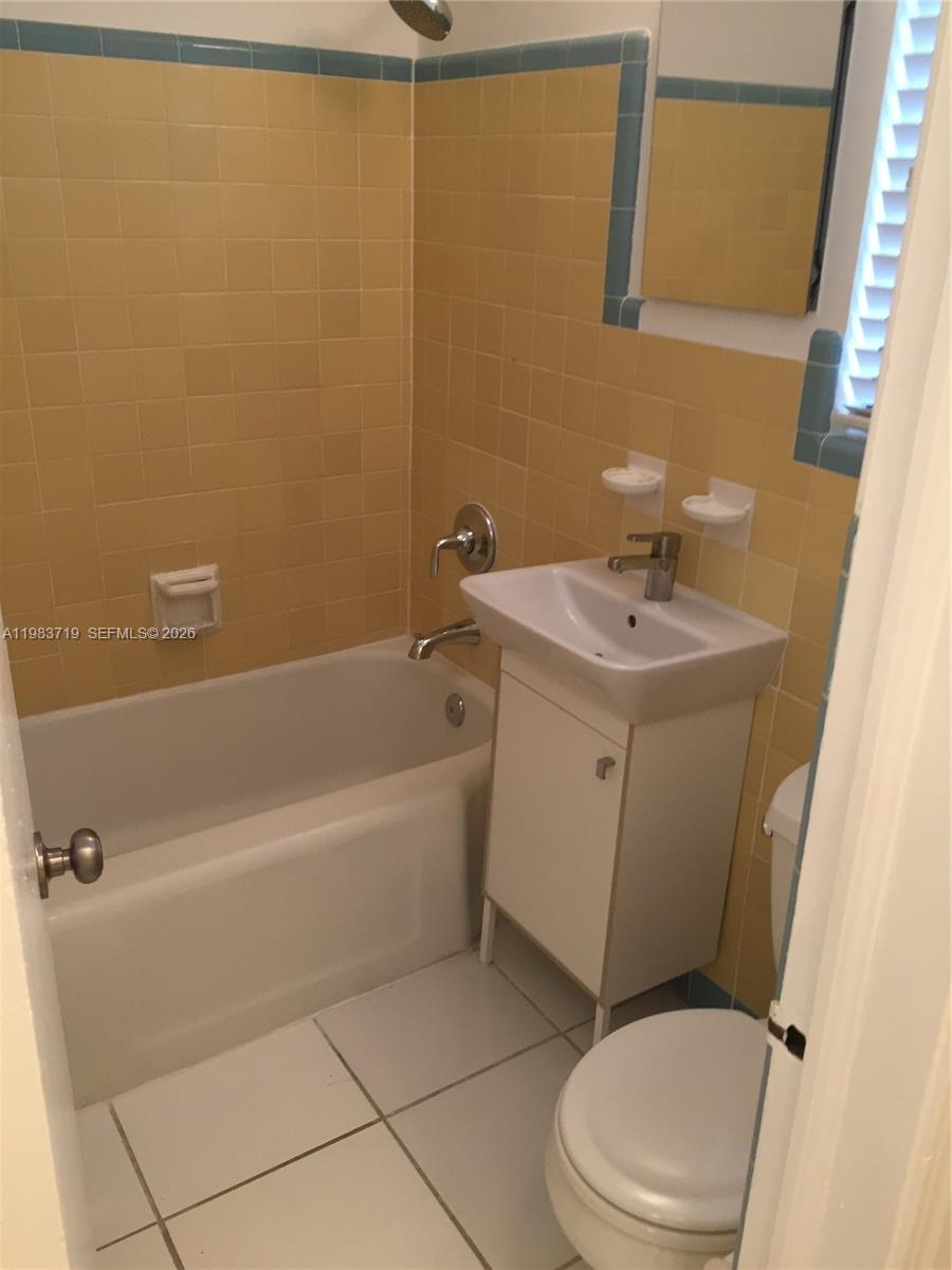 A small bathroom features yellow wall tiles, a white pedestal sink, and a bathtub — 535 74 # 7, Miami Beach FL 33141, MIAMI BEACH, FL