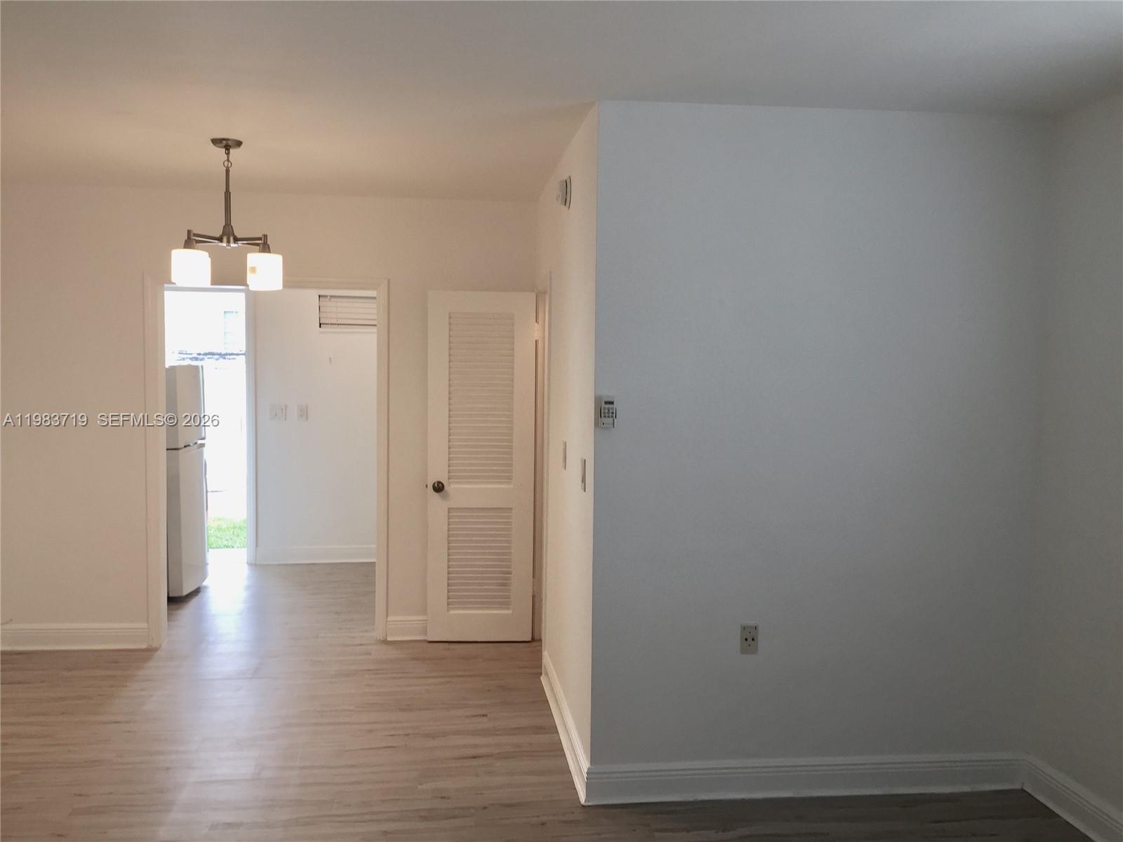 An interior view shows a white-walled room with light wood flooring and a louvered door — 535 74 # 7, Miami Beach FL 33141, MIAMI BEACH, FL