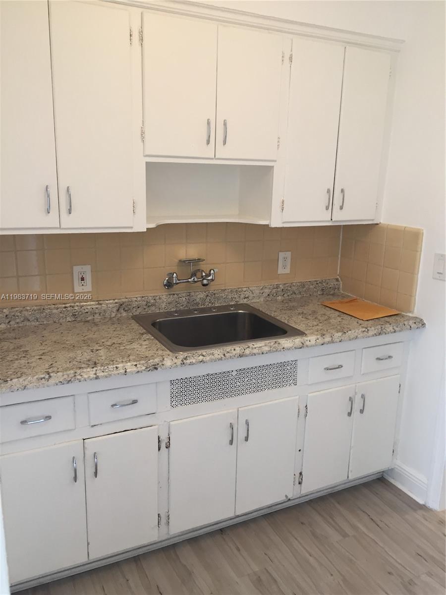 A kitchen features white cabinets, a granite countertop, a stainless steel sink, and tan backsplash — 535 74 # 7, Miami Beach FL 33141, MIAMI BEACH, FL