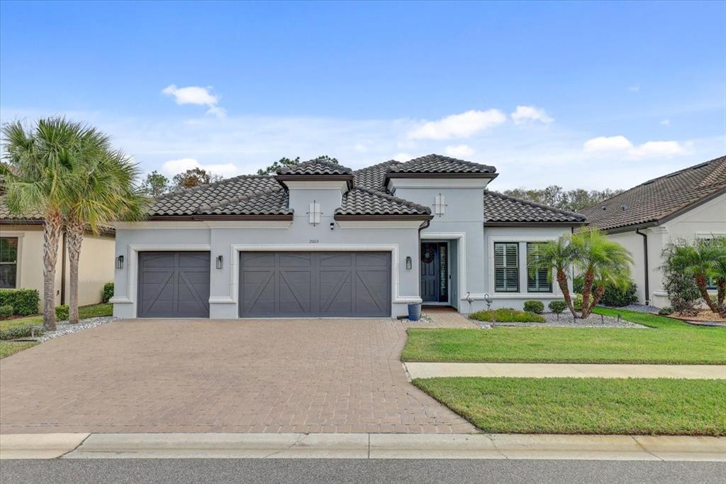 A single-story house with a gray exterior, tile roof, and a three-car garage — 20113 UMBRIA HILL DRIVE, TAMPA, FL