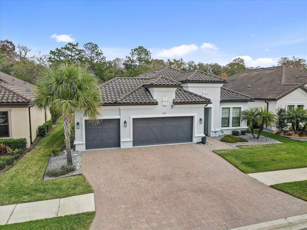 A single-story house with a gray tile roof, two garage doors, and a paved driveway — 20113 UMBRIA HILL DRIVE, TAMPA, FL