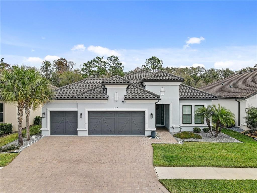 A single-story house with a gray tile roof, white stucco walls, and a three-car garage — 20113 UMBRIA HILL DRIVE, TAMPA, FL