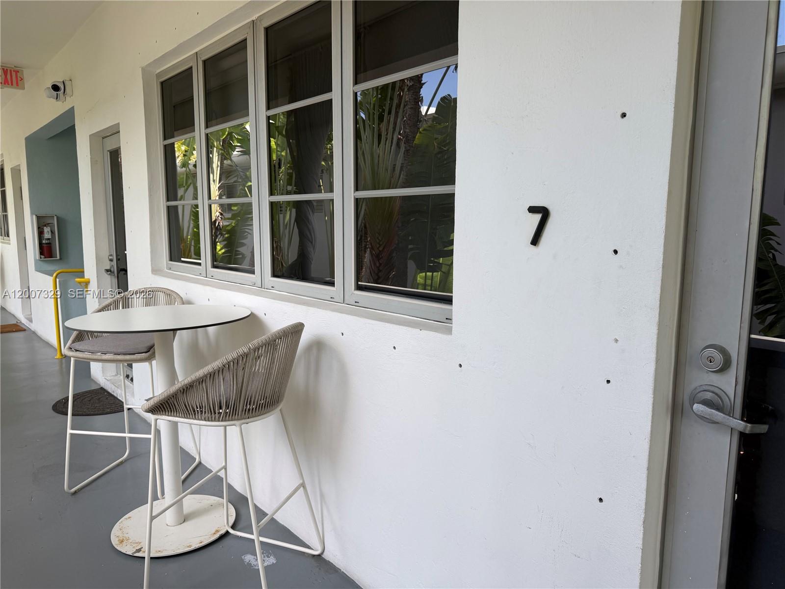 A small outdoor patio area features a bistro table with two chairs beside a window — 1551 Lenox Ave # 7, Miami Beach FL 33139, MIAMI BEACH, FL