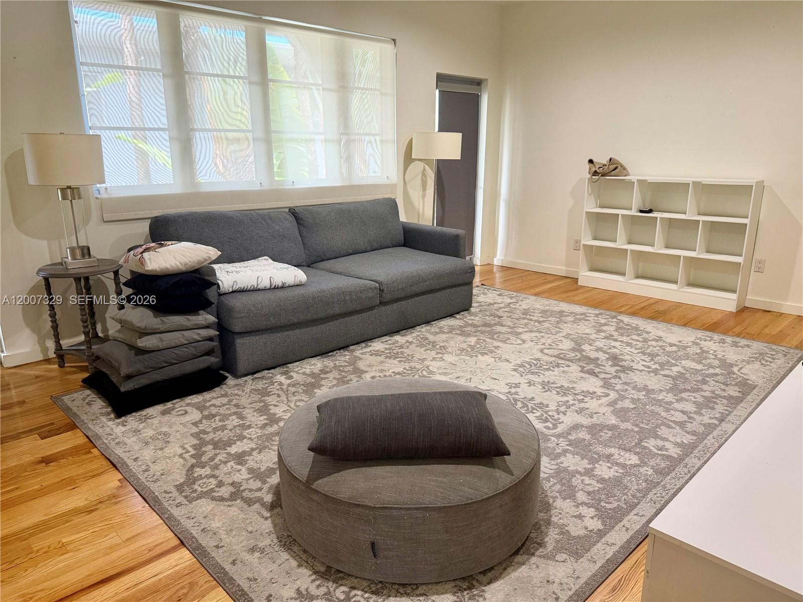 A living room features a gray sofa, a patterned area rug, and a white bookshelf — 1551 Lenox Ave # 7, Miami Beach FL 33139, MIAMI BEACH, FL