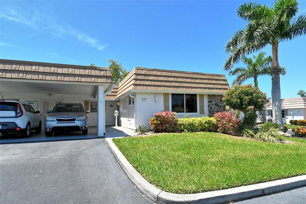 A single-story house with a carport, a front lawn, and a palm tree — 2308 WATERBLUFF PLACE UNIT V304, SARASOTA, FL