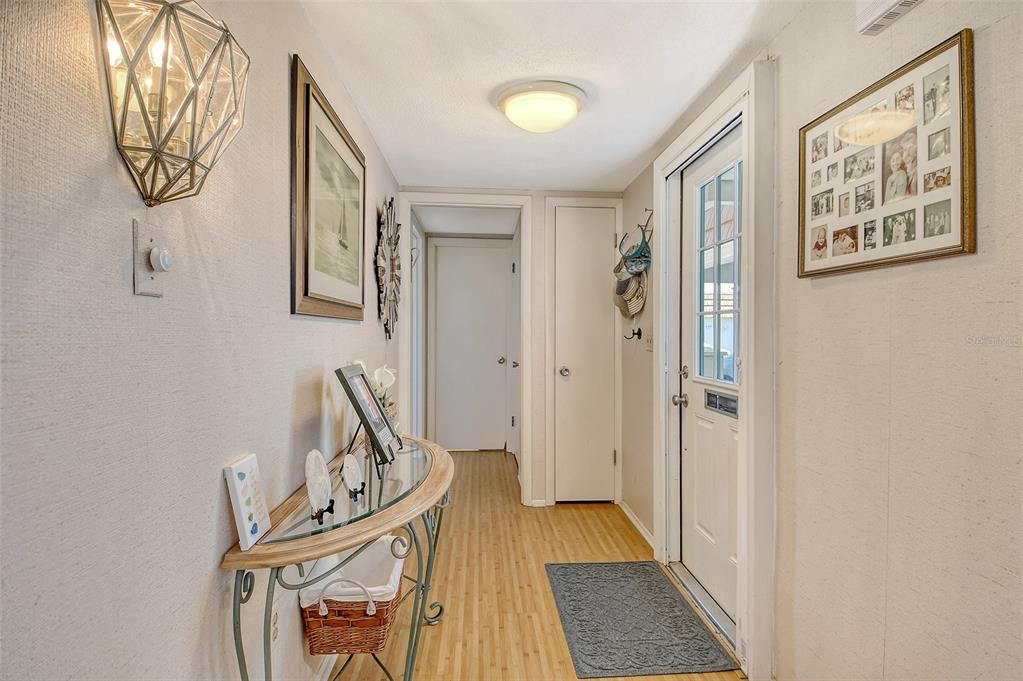 A hallway features a glass-topped console table, a white door, and a framed photo collage — 2308 WATERBLUFF PLACE UNIT V304, SARASOTA, FL