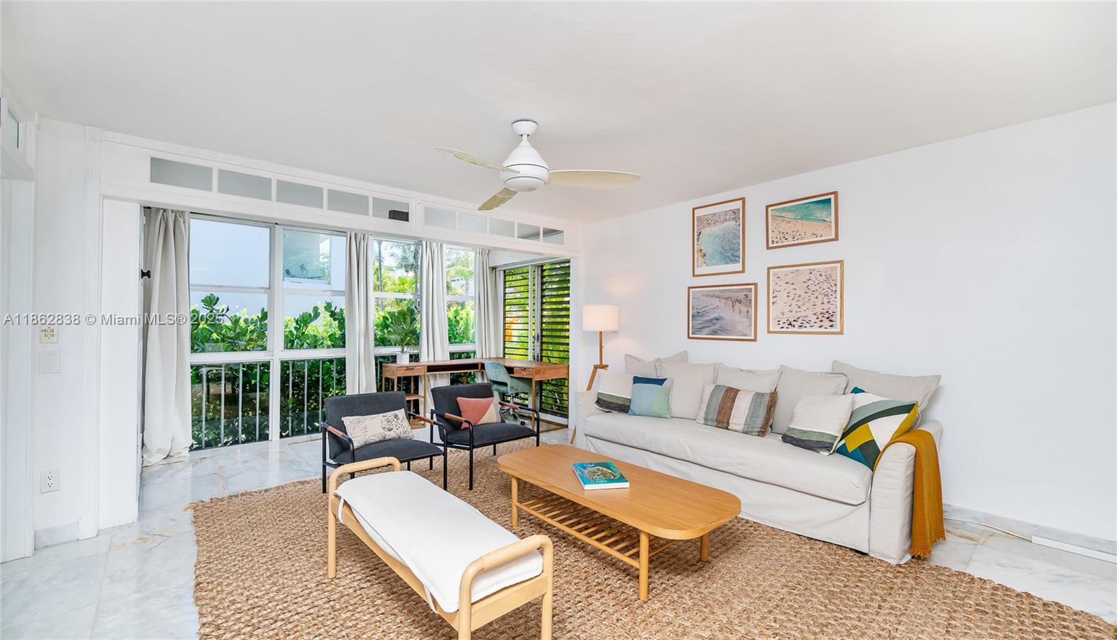 A bright living room features a beige sofa, wooden coffee table, and large floor-to-ceiling windows — 195 Sunrise Dr # 1, Key Biscayne FL 33149, KEY BISCAYNE, FL