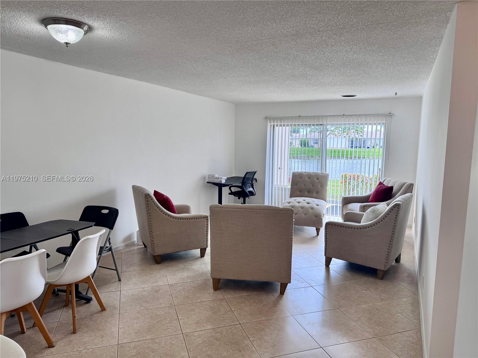 A living room with tile floors, several tufted armchairs, a dining set, and sliding glass doors — 8838 Bella Vista Dr, Boca Raton FL 33433, BOCA RATON, FL