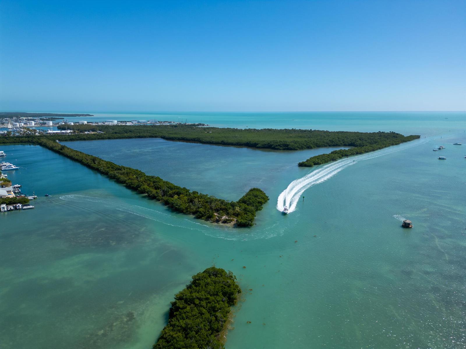 An aerial view shows a boat traveling through a channel between mangrove islands and water — 7000 5th Street, Key West FL 33040, KEY WEST, FL