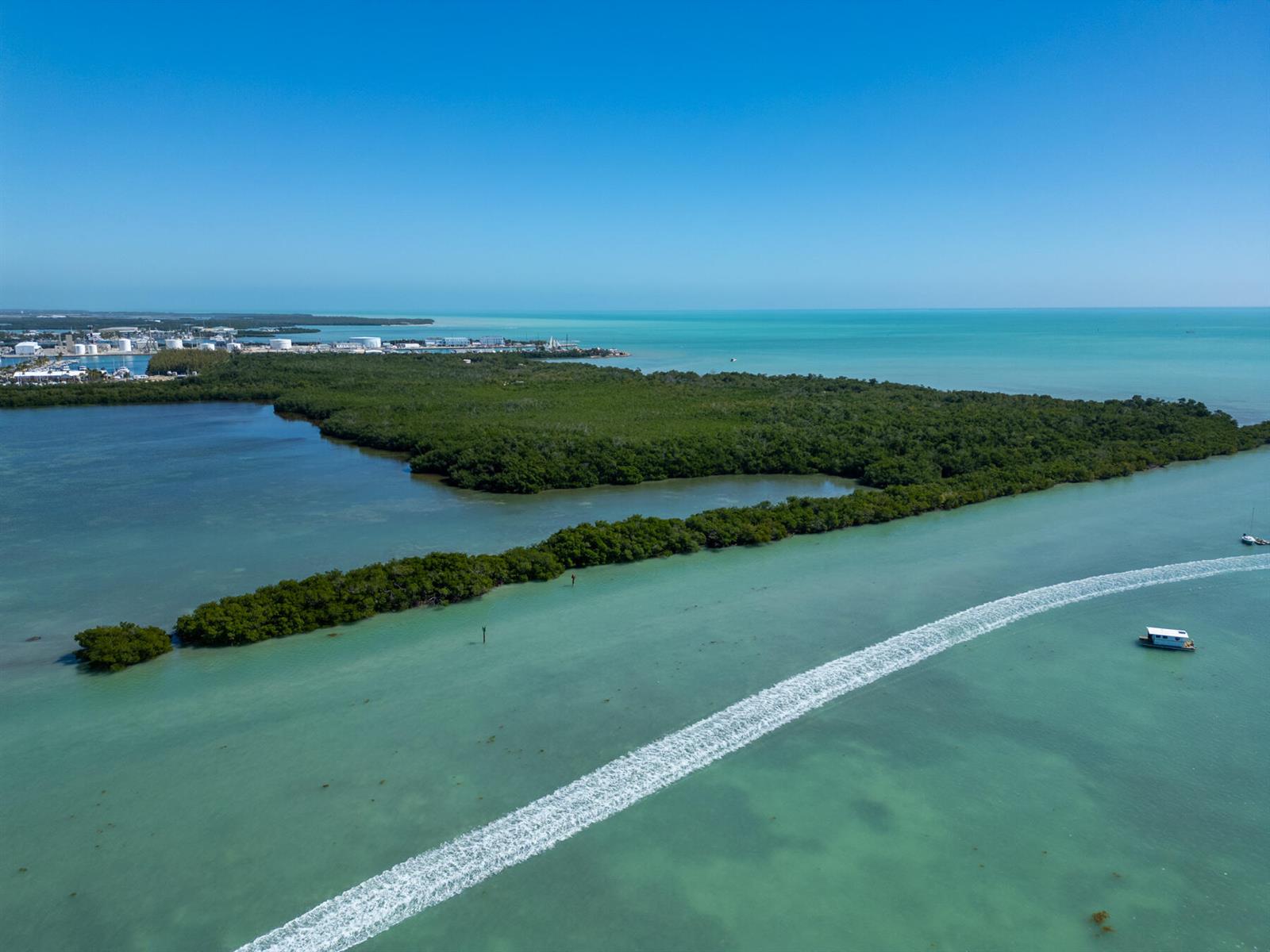 An aerial view shows a mangrove island surrounded by shallow turquoise water with a boat wake — 7000 5th Street, Key West FL 33040, KEY WEST, FL
