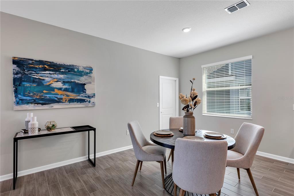 A dining room features a round table, four upholstered chairs, and a console table — 6092 MEDITATION DRIVE, CLERMONT, FL