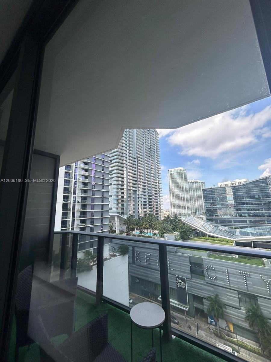A balcony with green turf flooring overlooks a city skyline and a large shopping center — 45 SW 9th St # 1409, Miami FL 33130, MIAMI, FL