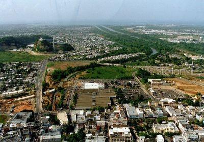 An aerial view of a town featuring a large shopping center, residential areas, and green space — 167 PR 167 INT. BETANCES ST., BAYAMON, PR