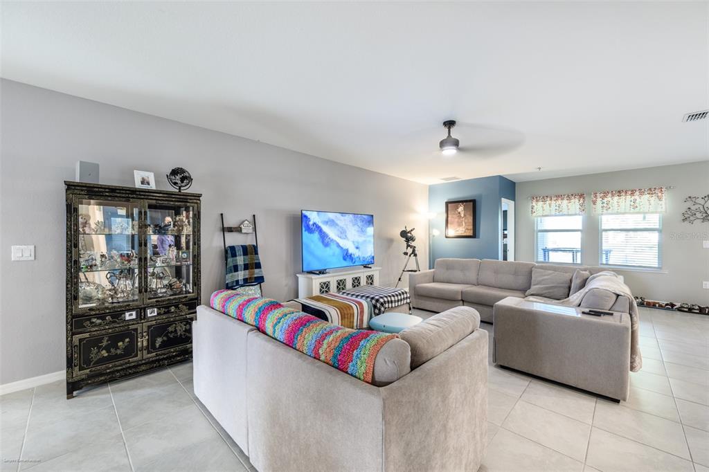 A living room features a grey sectional sofa, a television, and a black display cabinet — 25506 DOREDO DRIVE, PUNTA GORDA, FL