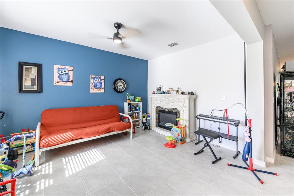 A living room features a blue accent wall, a red futon, and a fireplace — 25506 DOREDO DRIVE, PUNTA GORDA, FL