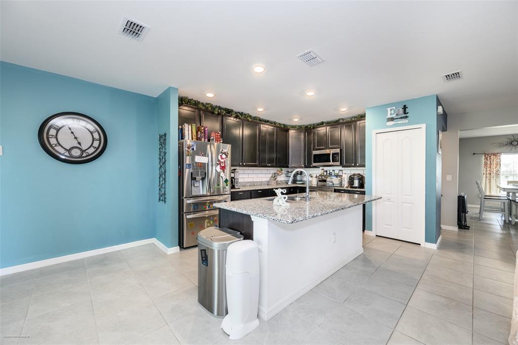 A kitchen features dark cabinetry, granite countertops, a center island, and blue accent walls — 25506 DOREDO DRIVE, PUNTA GORDA, FL
