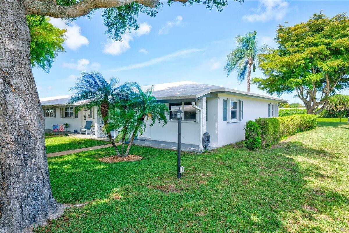 A white single-story house with a lawn, palm trees, and a large tree in front — 100 Leisure Lake Circle # 109, Boynton Beach FL 33426, BOYNTON BEACH, FL