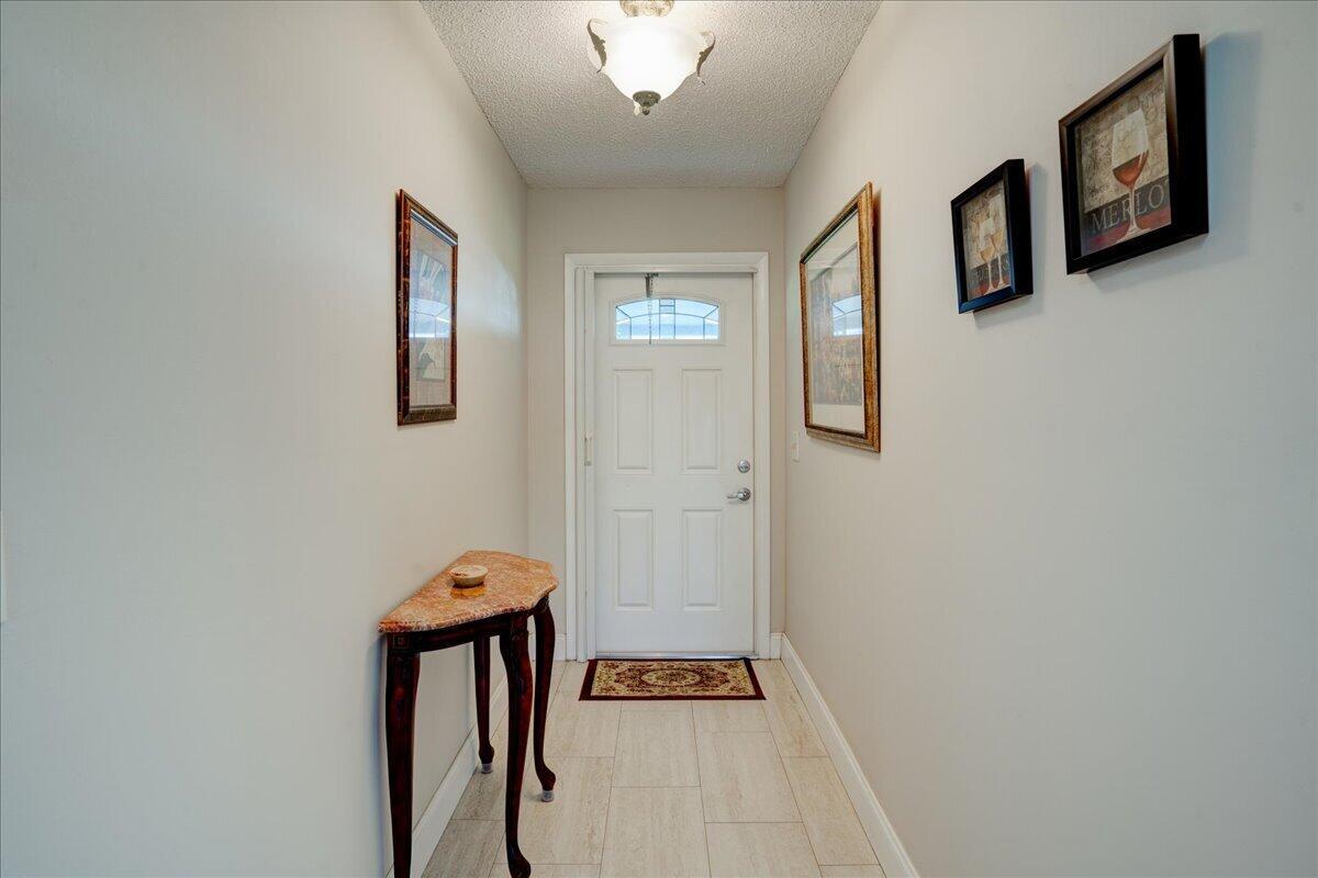 A foyer features a white front door, a marble-topped console table, and framed wall art — 100 Leisure Lake Circle # 109, Boynton Beach FL 33426, BOYNTON BEACH, FL