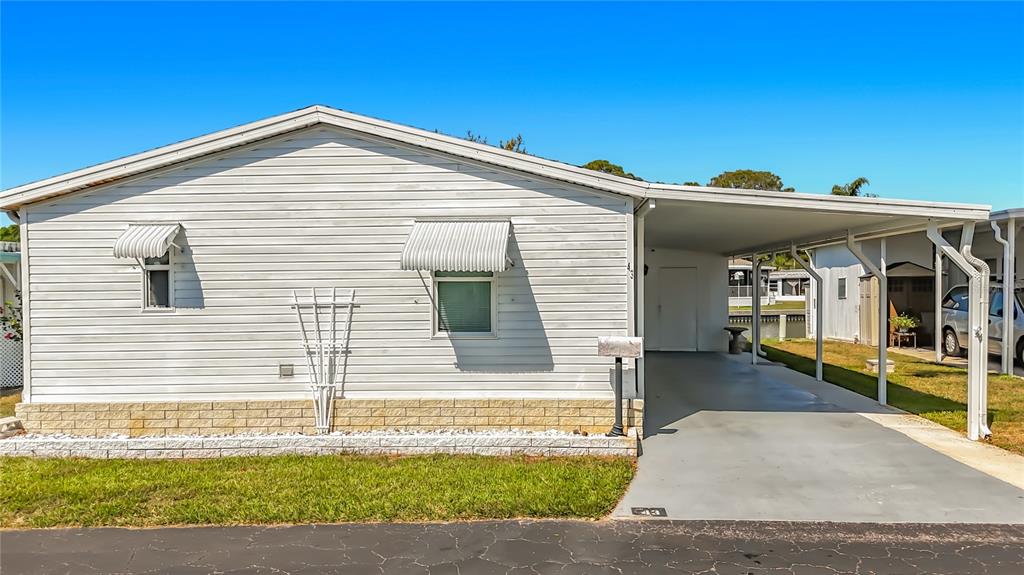 A single-story mobile home with white horizontal siding, a carport, and a brick-patterned base — 980 7TH STREET NW UNIT 43, LARGO, FL